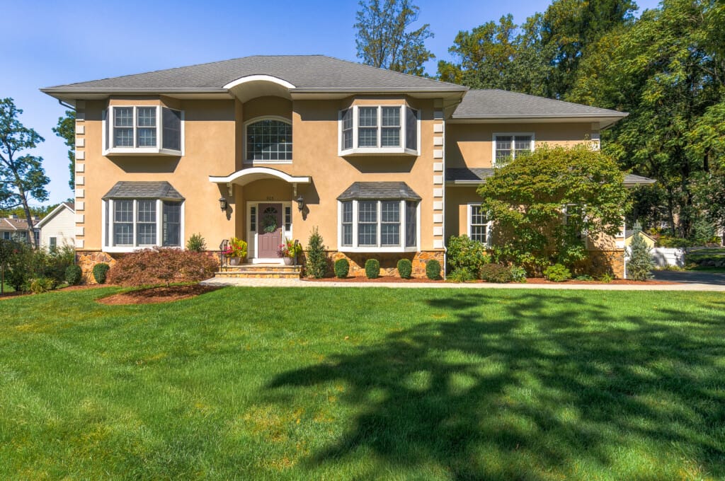 Luxury stucco home front exterior in Morris County NJ with symmetrical design, manicured lawn, and refined curb appeal