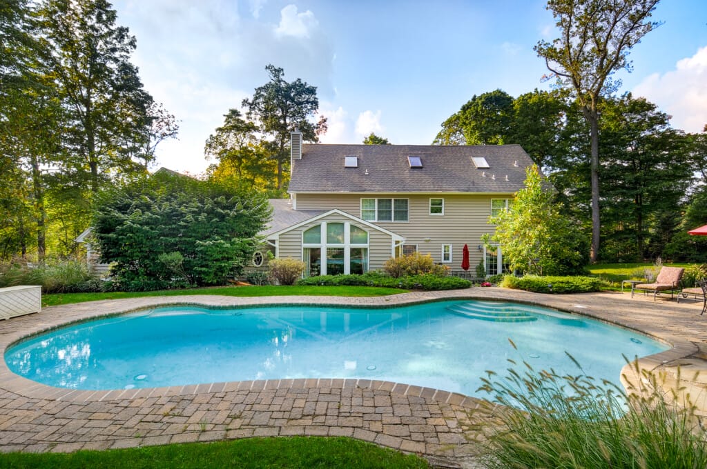 Luxury home backyard in Morris County NJ with in-ground swimming pool, patio, and landscaped yard