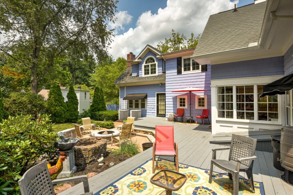 Cottage style home in Morris County NJ with backyard deck, fire pit seating area, and landscaped outdoor living space