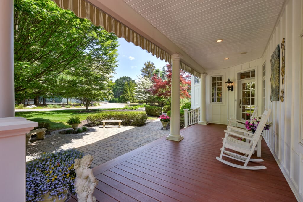 Front porch view in Morris County NJ with rocking chairs overlooking landscaped yard and paver walkway