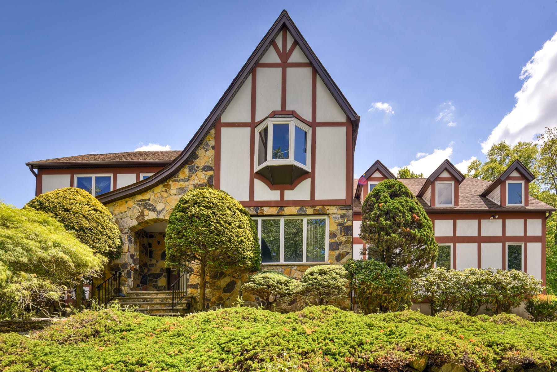 Tudor style home in Morris County NJ with steep gable roofline, half timber detailing, and stone exterior
