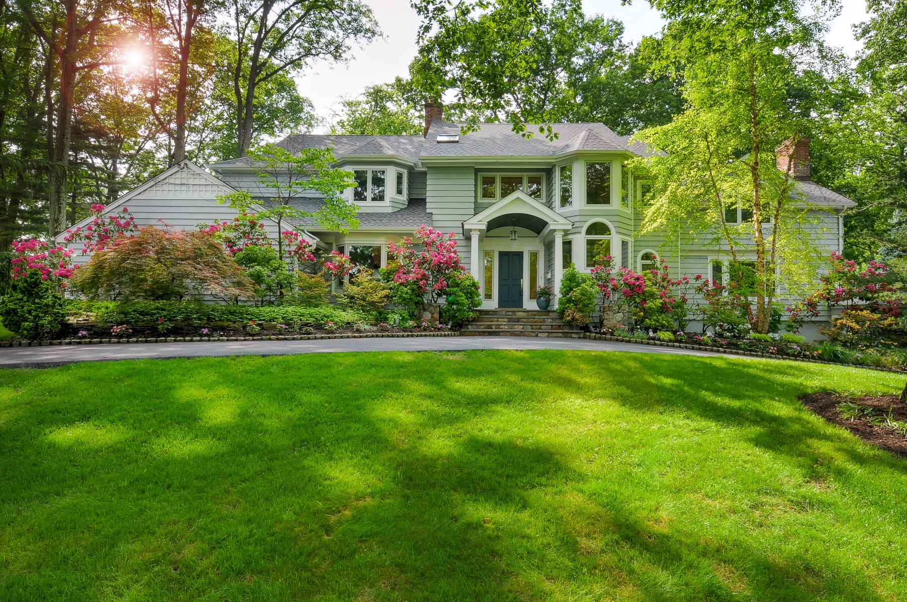 Luxury home front exterior in Morris County NJ with landscaped yard, flowering shrubs, and circular driveway