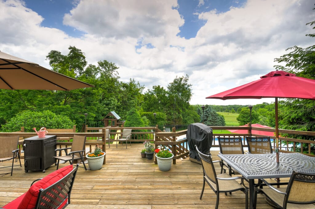 Luxury home deck in Morris County NJ with outdoor dining, grill area, and scenic backyard views