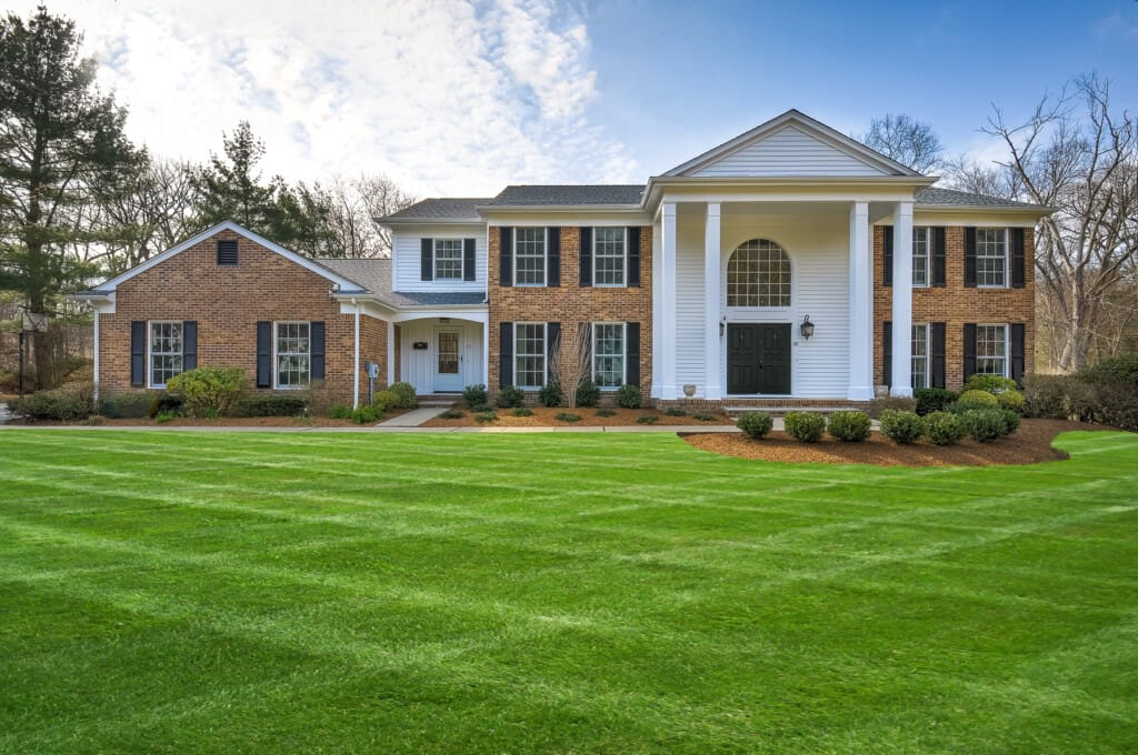 Luxury colonial home front elevation in Morris County NJ with columns, symmetrical design, and manicured lawn