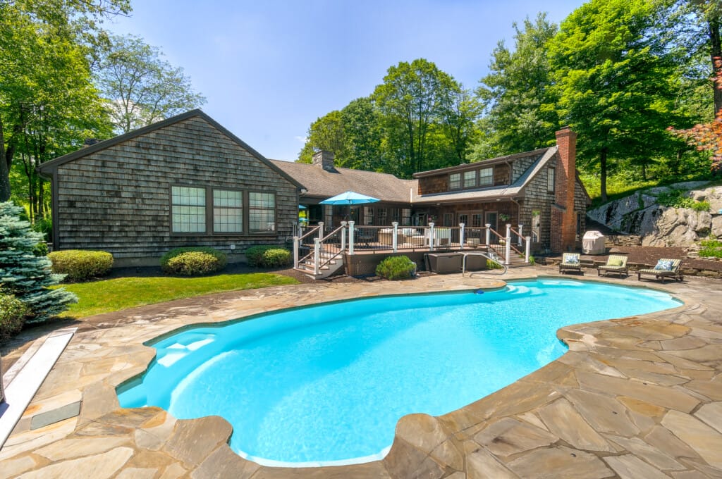 Luxury backyard pool in Morris County NJ with natural stone patio, elevated deck, and private outdoor living space