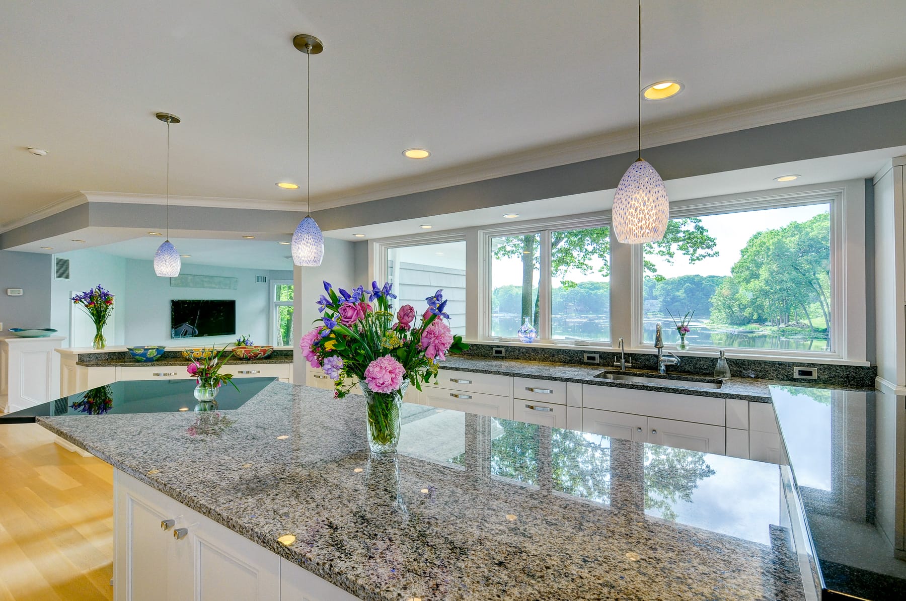 Open concept kitchen in Morris County NJ with large island, pendant lighting, and scenic water view through wide windows
