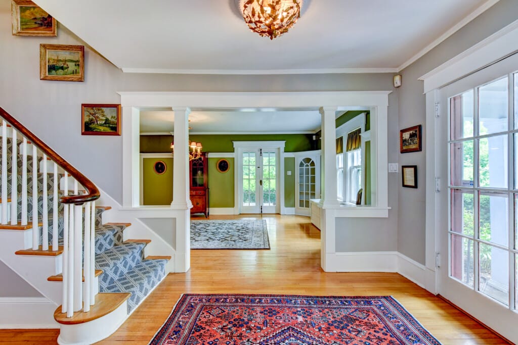 bright open foyer in Morris County NJ with hardwood floors staircase and columned entry leading to living space