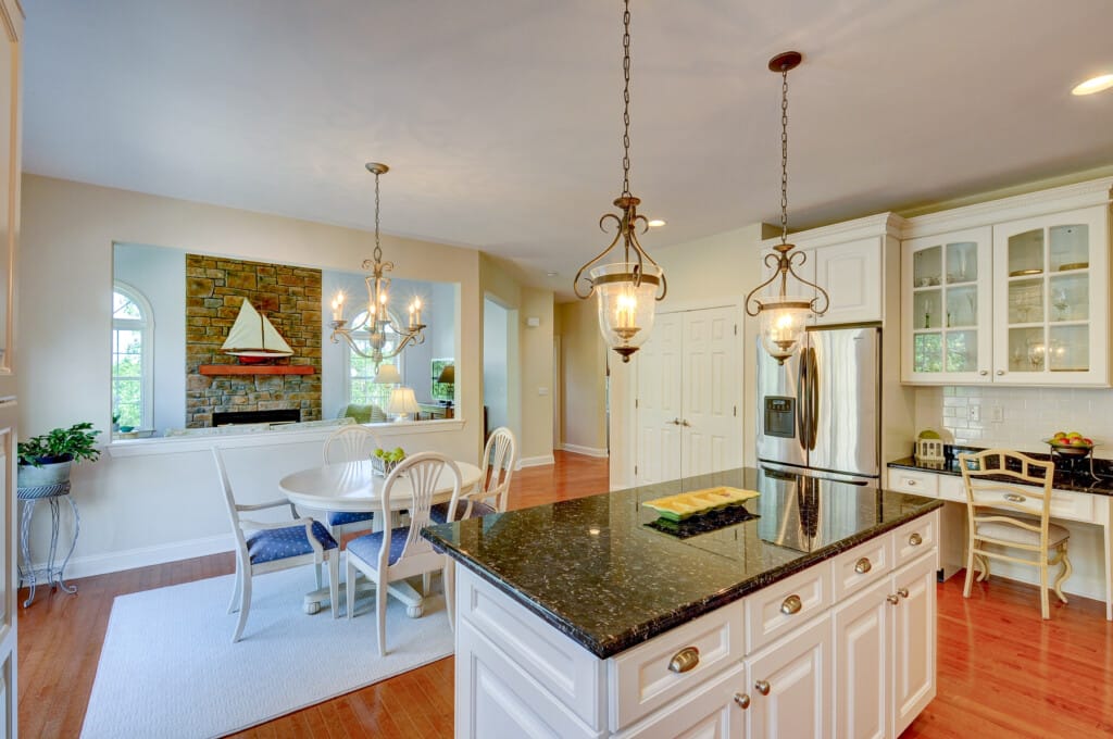 Open kitchen and dining area in Morris County NJ with island, breakfast nook, and view into living room with fireplace