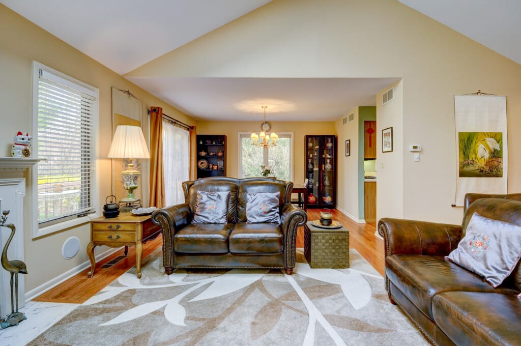 Living room in Morris County NJ with leather seating, hardwood floors, and open flow to dining area
